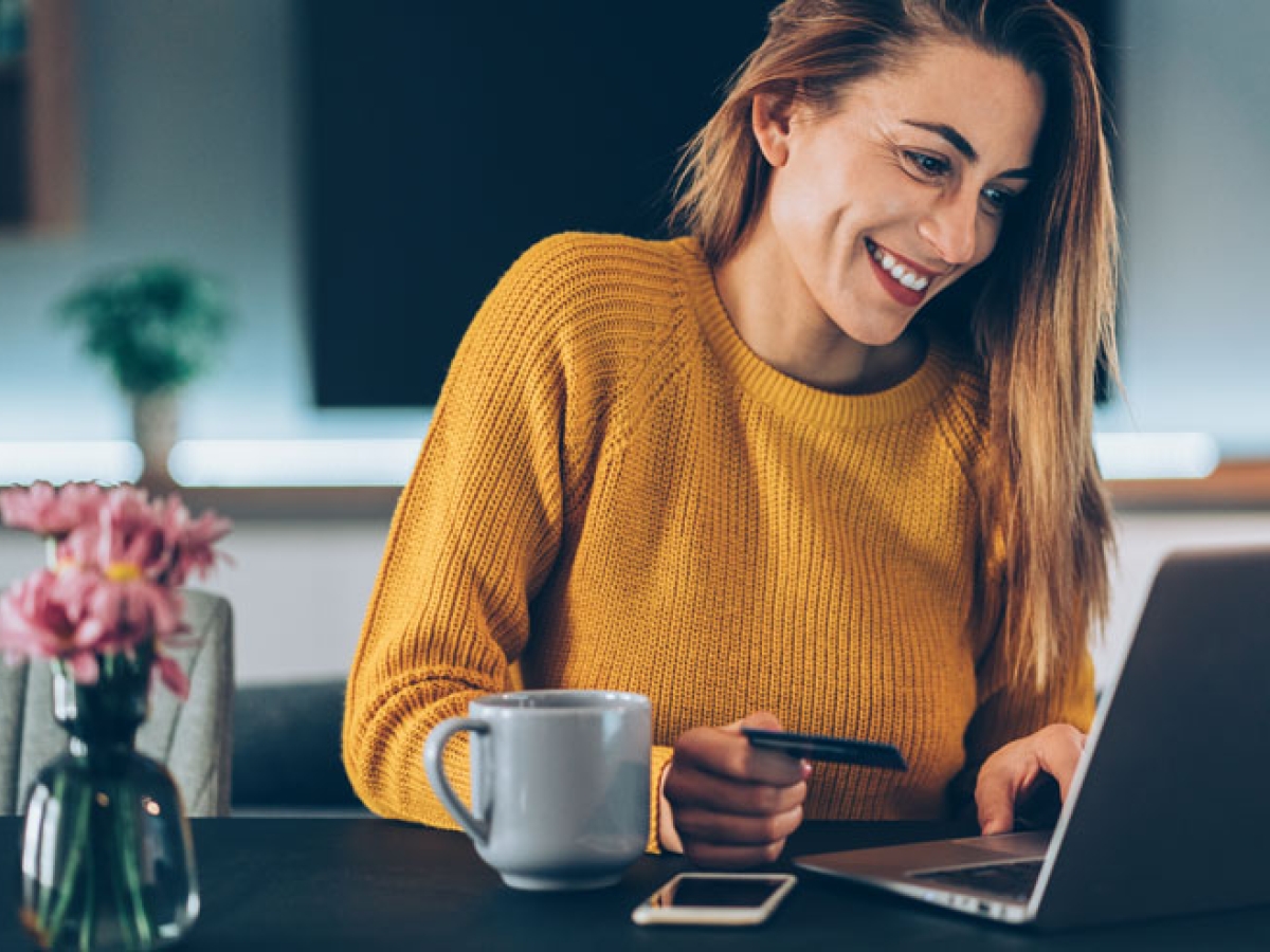 Woman in front of her computer using her credit card to pay online Woman in front of her computer using her credit card to pay online